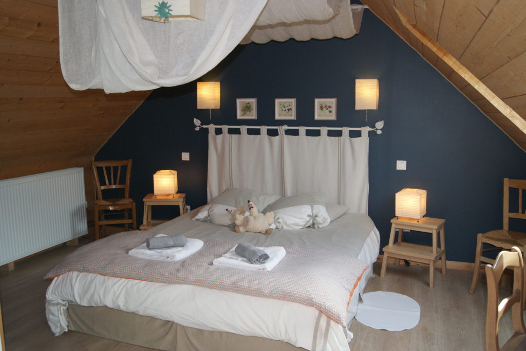 Photographie de la chambre du gîte, dans un style pittoresque aux teintes boisées et bleutées